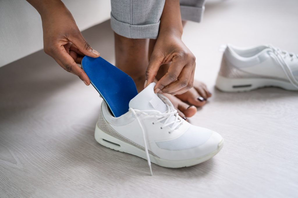Man inserting insole into shoe.